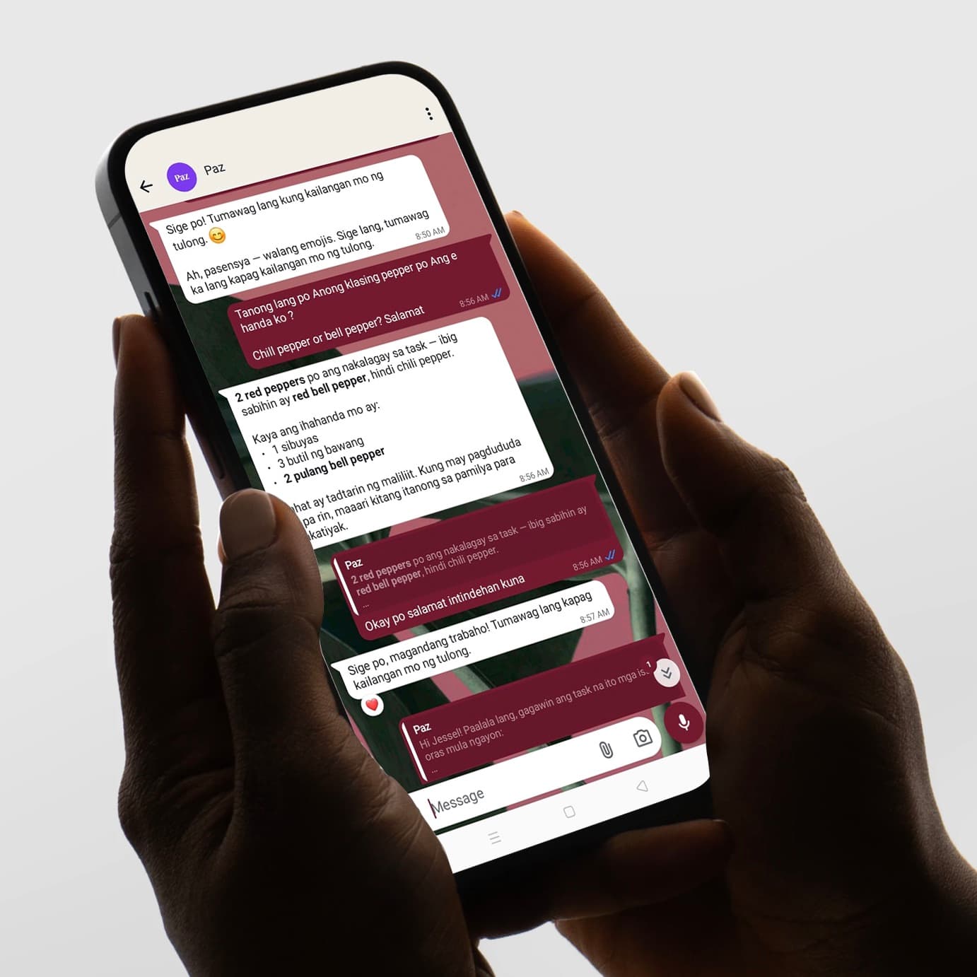 A pair of hands holding a phone showing a WhatsApp conversation with Paz in Tagalog.